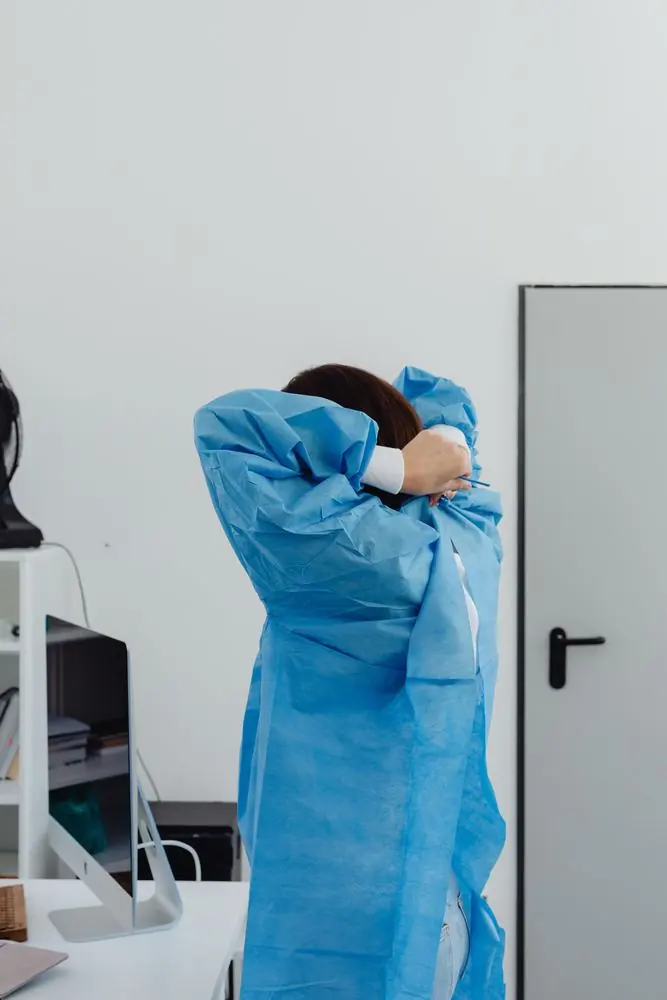 Labortechnikerin in blauem Schutzkittel in einem Reinraum